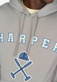 Szara bluza z kapturem z wypukłym napisem "HARPER" w niebieskim kolorze z białymi konturami oraz grafiką niebieskiego kasku budowlanego i skrzyżowanych narzędzi z przodu.