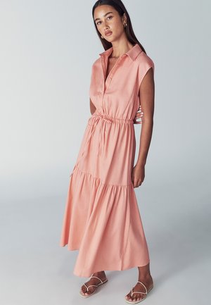 Roza, višeslojna maksi haljina s kratkim rukavima, kragnom i strukom s užetom. Napravljena od lagane tkanine, s detaljima na dugmadima i lepršavim suknjom.