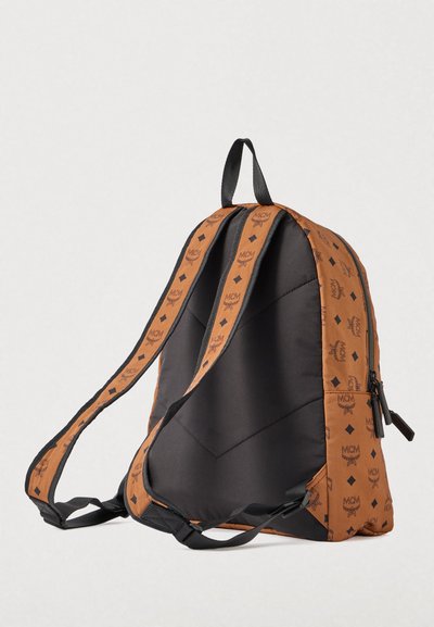 Sac à dos noir et marron avec des bretelles réglables, présentant des logos MCM répétés et des motifs en diamant, montré depuis le côté arrière rembourré.