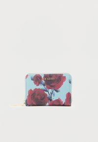 Portofel compact cu fermoar, având un fundal albastru cu imprimeuri de trandafiri roșii și logo-ul "Ted Baker" auriu pe față.