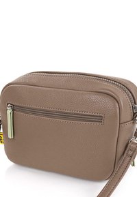 Bolso cruzado de cuero marrón con un acabado texturizado, que cuenta con un bolsillo frontal con cremallera y una correa desmontable. Acentuado con herrajes en plata.