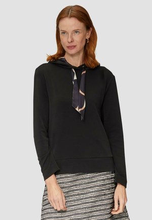 Zwarte hoodie met een gestippelde das, met lange mouwen en een relaxte pasvorm. Gedeeltelijk gedragen met een gestructureerde rok, wat zorgt voor een casual uitstraling.