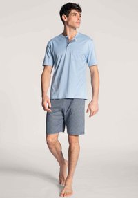 Lichtblauw kortemouwen overhemd met een zak en een geruite patroonaccent. In combinatie met marineblauwe geruite shorts. Katoenmengsel materiaal.