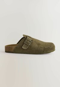 Olive green suede slip-on shoe with a rounded toe, featuring a buckle accent and a textured cork sole. Flat design with no laces.