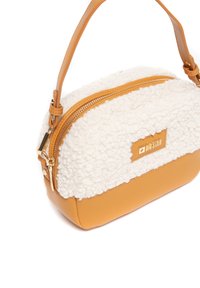Torba na ramię z puszystą białą górą, brązową ekologiczną skórą na dole, złotym zamkiem i wytłoczonym logo z przodu. Kompaktowy i zorganizowany kształt.