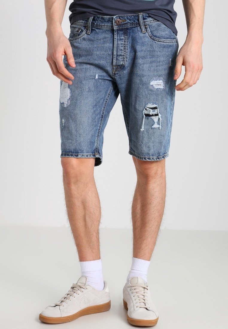 Shorts de mezclilla en azul claro con corte relajado. Presentan bordes deshilachados y detalles desgastados en la parte delantera, incluyendo secciones rasgadas.