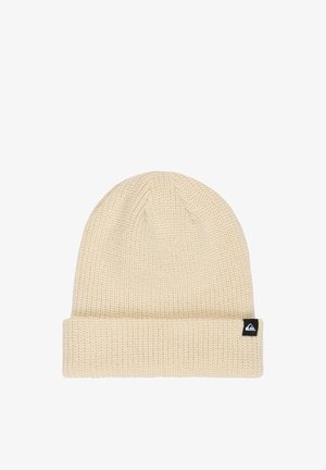 Beżowa dziana czapka typu beanie z podwiniętym mankietem i małą czarną metką z logo po boku.
