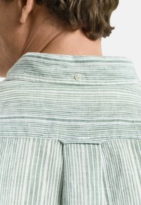 Camicia a righe verdi e bianche con colletto button-down, tessuto testurizzato e yoke con cucitura centrale e dettaglio di bottone.