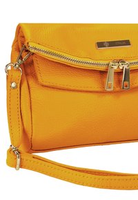 Gelbe Lederhandtasche mit strukturierter Oberfläche, ausgestattet mit einem Reißverschluss oben, silbernen Beschlägen und einem abnehmbaren Riemen.