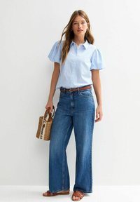 Blue and white striped short-sleeve shirt, high-waisted wide-leg jeans, brown sandals, and a woven bag with black text. Casual outfit.