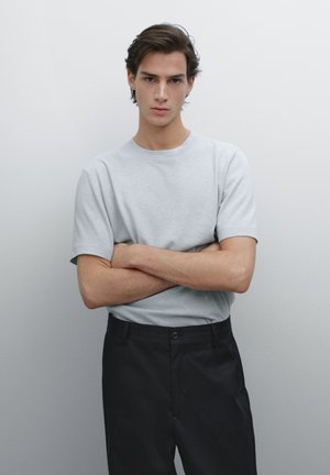 Gray short-sleeve t-shirt made of cotton, paired with black trousers. The t-shirt has a crew neck and relaxed fit. Simple design, no patterns.