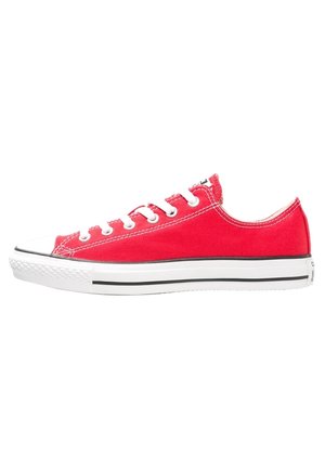 Czerwony niski sneaker z materiału typu canvas z białym gumowym noskiem, białymi sznurówkami i białą podeszwą z czarnym paskiem.
