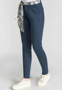 Pantalones ajustados de color azul oscuro con un cinturón de estampado de piel de serpiente. Fabricados con una mezcla de algodón, cuentan con bolsillos delanteros y una textura suave.