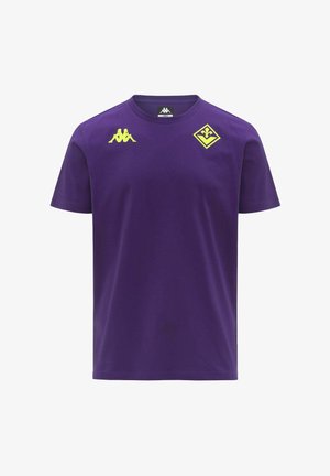 T-shirt viola a maniche corte con logo Kappa giallo sul petto destro e un emblema giallo a forma di diamante con una fleur-de-lis sul petto sinistro.