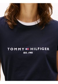 Námořnické bavlněné tričko s bílým žebrovaným kulatým výstřihem, vyšívaným logem "TOMMY HILFIGER" a "EST. 1985" pod textem.