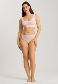 Set di abbigliamento sportivo rosa chiaro composto da un crop top con scollatura a barca e spalline spesse, abbinato a slip bikini a vita alta, realizzato in tessuto morbido.
