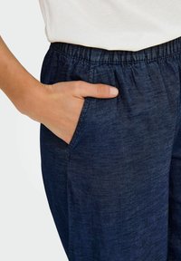 Donkerblauwe instapbroek met een rekbare tailleband en zijzakken. De stof heeft een gladde textuur met subtiele kleurvariaties.