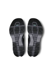 Semelles de chaussures de sport noires avec des crampons en caoutchouc épais, présentant un motif texturé pour l'adhérence et un intermédiaire gris avec des accents bleu clair.