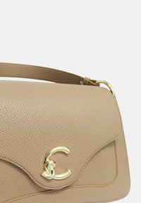Borsa a tracolla in pelle beige con finitura texturizzata, patta curva e un accento hardware in tonalità oro con logo sulla parte anteriore. Include una tracolla regolabile.