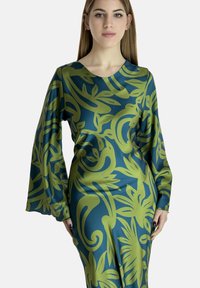 Langærmet kjole med et grønt botanisk print på en mørkeblå baggrund. Glat stof med en tætsiddende stil og rund halsudskæring.
