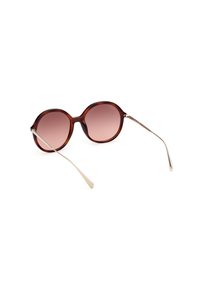 Occhiali da sole rotondi e marroni con lenti rosa sfumate. Bracci sottili in metallo che si curvano verso le punte. Montatura in plastica lucida senza dettagli hardware visibili.