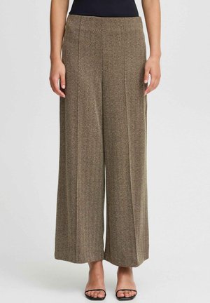 Brune bredbenede bukser med et herringbone-mønster, der har en høj talje og en glat tekstur, parret med sorte sandaler med åben tå.