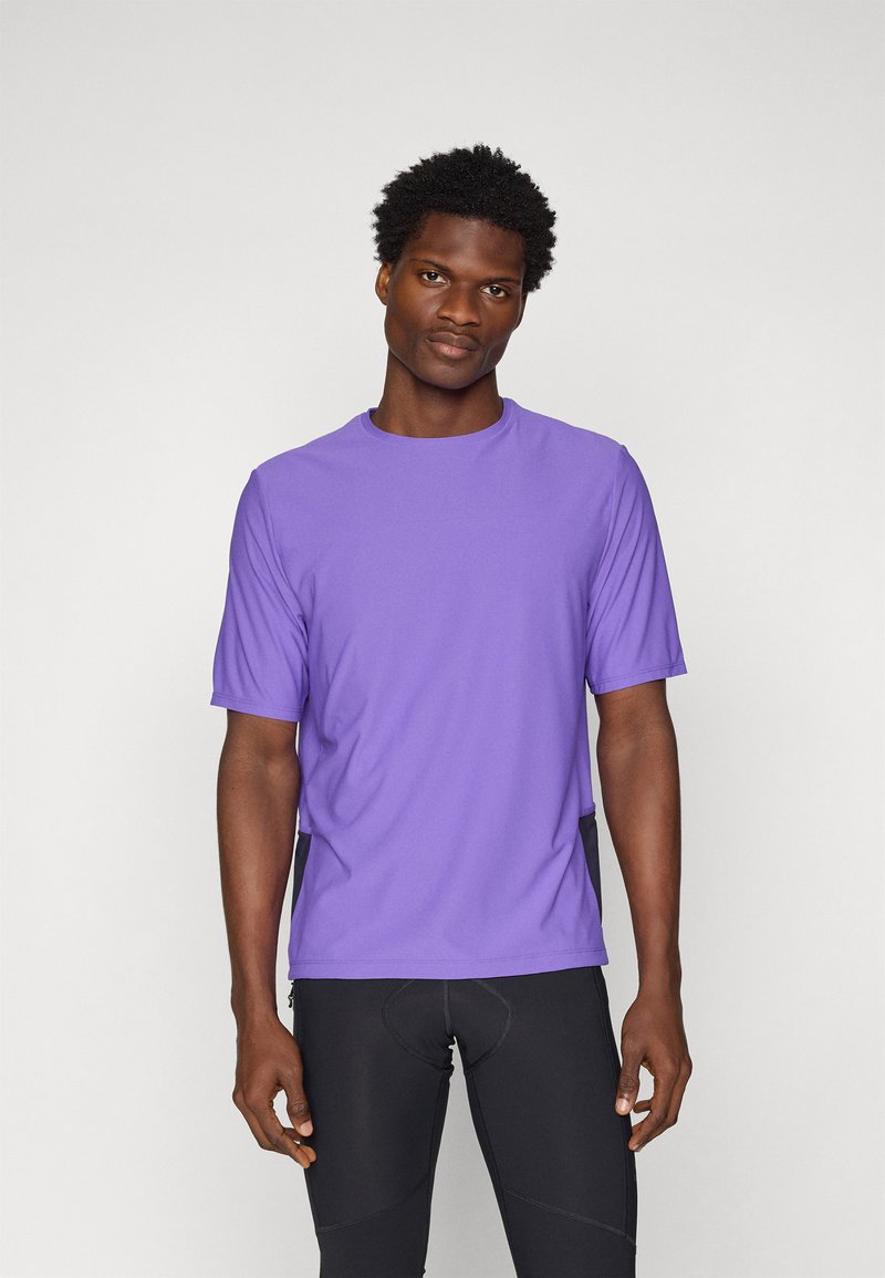 Camiseta deportiva de manga corta en color púrpura con cuello redondo, fabricada en un tejido ligero. Presenta un corte holgado y detalles de costura sutiles.