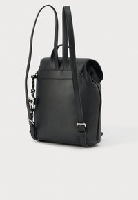 Juodas odinis kuprinė su dviem reguliuojamomis petnešėlėmis ir dekoratyvine juoda virvele su sidabriniu pakabuku, pritvirtintu šone.