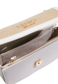 Bolso de mano de cuero blanco con parte superior beige con patrones, herrajes dorados, bolsillo interior con cremallera y dos compartimentos, con una elegante forma rectangular.