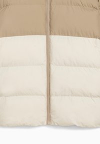 Giacca a vento trapuntata beige e crema con zip centrale e dettagli di cuciture orizzontali.