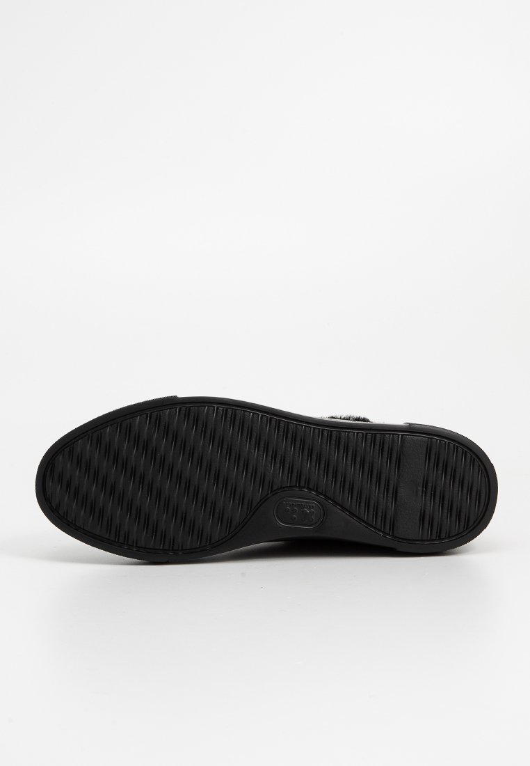 Czarny obuwie z gumową podeszwą z teksturowanym wzorem i okrągłym logo. Górna część wykonana jest z miękkiego materiału o puszystej fakturze.