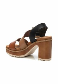 Sandalias de plataforma de cuero marrón y negro con grueso tacón cuadrado, diseño de tiras cruzadas y plantilla de corcho texturizado. Acento de costura ligera en la suela.