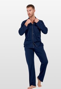 Conjunto de pijama azul marino en una tela suave, que incluye una camisa abotonada con un bolsillo y detalles en contraste, combinada con pantalones a juego.