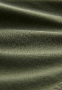 Material textil de culoare verde măslin, cu o suprafață texturată, prezentând ondulații subtile și un țesut fin, ce indică durabilitate și versatilitate.