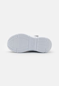 Semelle de basket blanche avec un motif de grip texturé, logo de marque et rainures de relief prononcées pour l'adhérence. Matériau lisse, semblable au caoutchouc.