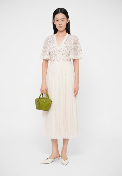 Rochie albă ușoară cu bodice brodat cu motive florale, mâneci transparente și fustă plisată; asortată cu o geantă mică verde și pantofi cu vârf ascuțit.