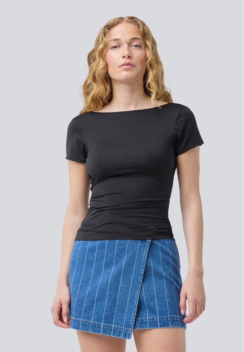 Black fitted short-sleeve top paired with a blue denim skirt featuring white vertical stripes and a wrap design. Simple and streamlined.