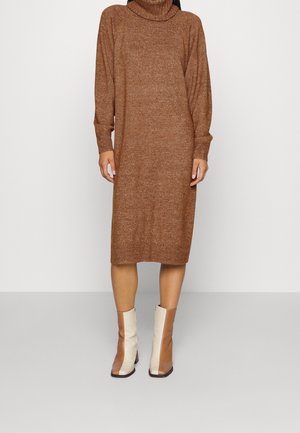 Ruskea neulottu mekko, jossa korkea mock-kaulus ja resorit hihansuissa, polvipituinen ja rento istuvuus. Yhdistetty kaksivärisiin nilkkureihin.