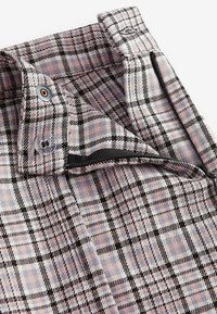 Karierte Button-Down-Bluse mit rosa, grau und schwarzen Mustern. Hergestellt aus einem Stoff mit weicher Textur. Verfügt über eine Brusttasche und einen Reißverschlussdetails.