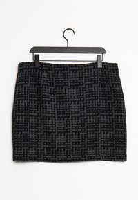 Falda con estampado en negro y gris, de tela texturizada, con forma recta y cintura, colgando de un perchero de plástico negro.