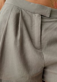 Šedé lněné šortky s skládacím předním dílem, které mají hladký pas a boční kapsu pro pohodlí. Lehce strukturovaný materiál s jemným leskem.