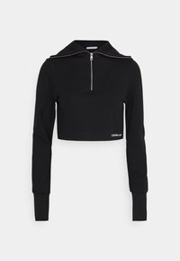 Svart kort sweatshirt med dragkedja vid kragen, ribbad textur och långa ärmar. Har en liten vit logotyp vid fållen.