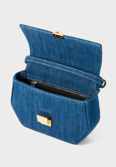 Sac en denim avec une forme structurée, quincaillerie dorée et une poche zippée à l'intérieur. Présente un rabat et des coutures contrast�ées.