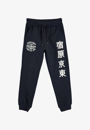 Donkerblauwe joggerpants gemaakt van een katoenmix. Voorzien van een elastische tailleband, trekkoord en witte bedrukte tekst aan beide zijden.