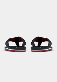 Μαύρα σανδάλια με κόκκινη εσωτερική επένδυση, διαθέτουν ρυθμιζόμενους ιμάντες και υφασμένο πέλμα. Το παπούτσι έχει μια στρωματοποιημένη μεσαία σόλα σε λευκό και κόκκινο χρώμα.