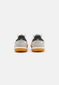 Nike tenisice s gornjim dijelom od sivoj suede, crnim detaljima na petama i potplatom od gume. Uključuju vidljivo brendiranje na petama.
