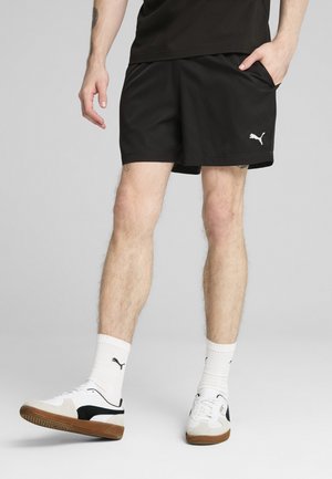 Juodi sportiniai šortai su šoninėmis kišenėmis ir balta Puma logo. Derinami su baltais sportiniais bateliais su juodais akcentais ir baltais kojinėmis.