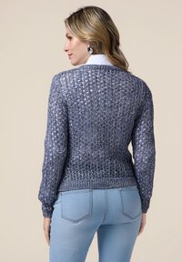 Suéter de punto en azul oscuro con un tejido texturizado de trama abierta, mangas largas y dobladillo acanalado ajustado. Combinado con jeans azul claro, visto desde la espalda.