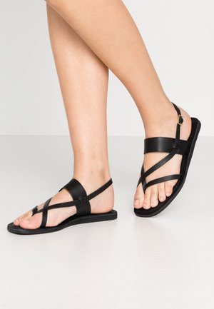 Sorte læder sandaler med flere krydsende stropper og en flad sål. Justerbar ankelrem med en guld spænde detalje.