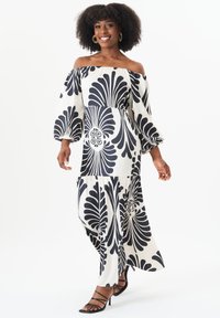 Off-the-shoulder maxi dress in black and white, featuring bold floral patterns, puffed sleeves, and a flowing silhouette.